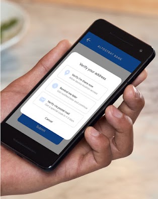 Person holding phone with three options to verify their address: "Verify I'm there now", "remind me later", or "verify via postal mail"