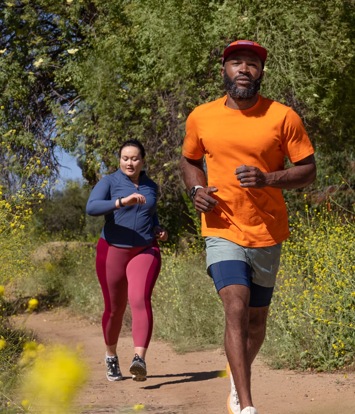 Two people running on a trail lined with trees. Both are wearing Google Pixel Watch 2.