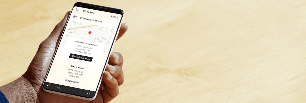 Hand holding a mobile phone showing corrected address