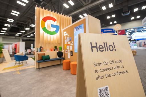 Photo of Google booth with sign in the front that says 'Hello! Scan the QR code to connect with us after the conference.'